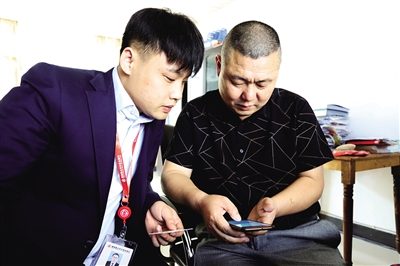 4 客户经理指导客户通过手机银行操作贷款业务。.jpg